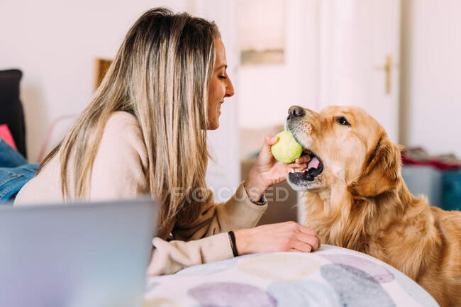 Italia, Mujer joven jugando con el perro en casa - foto de stock