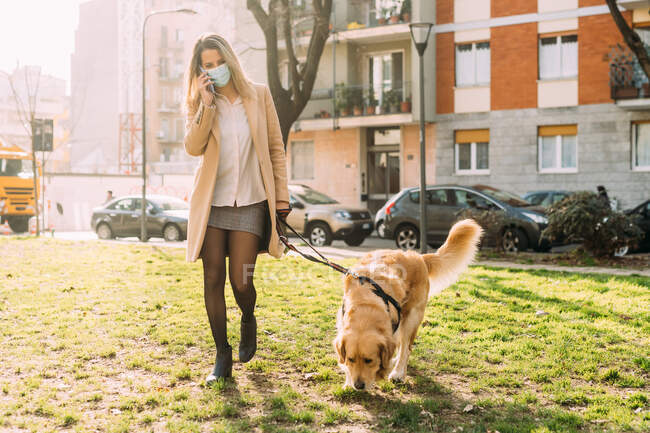 Italia, Mujer joven y perro paseando sobre hierba - foto de stock