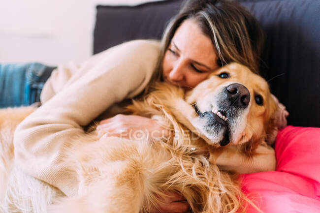 Italia, Mujer joven y perro relajándose en la cama - foto de stock