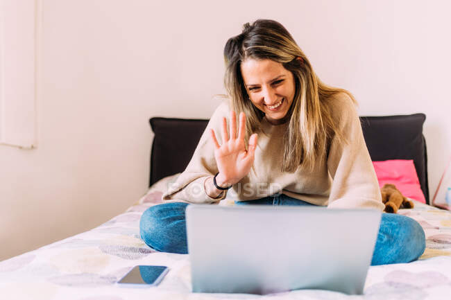 Italy, Young woman using laptop on bed — Stock Photo