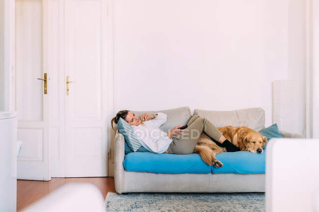 Italien: Junge Frau und Hund entspannen sich auf dem Sofa — Stockfoto