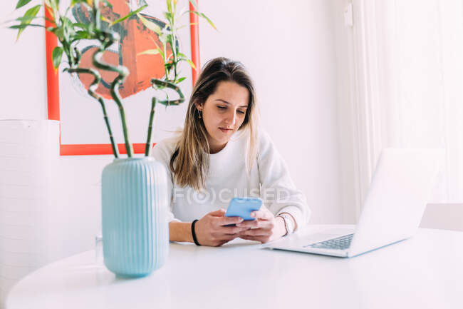 Italy, Young woman using laptop and smartphone at home — Stock Photo