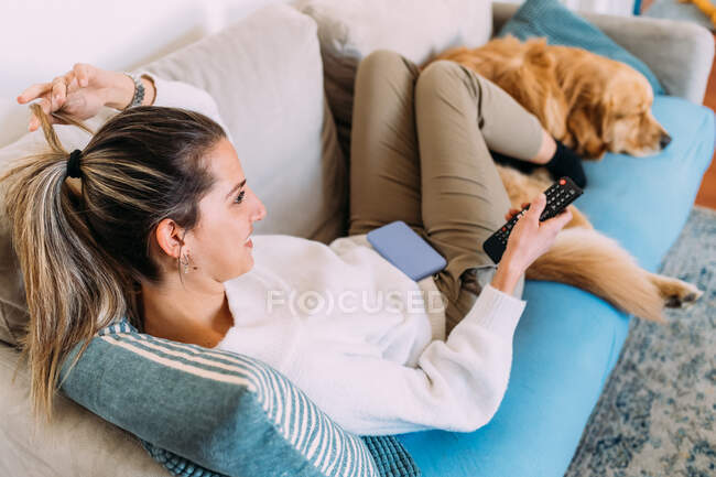 Italien: Junge Frau und Hund entspannen sich auf dem Sofa — Stockfoto