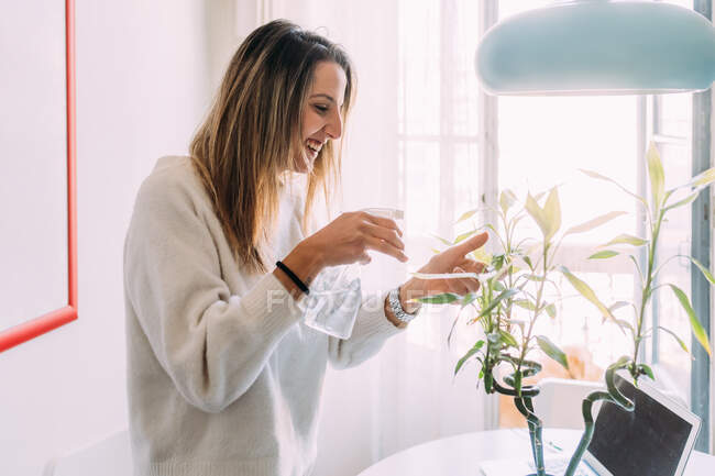 Italy, Woman spraying flowers at home — Stock Photo