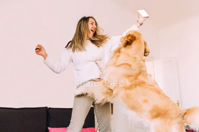 Италия, Молодая женщина играет с собакой дома — стоковое фото