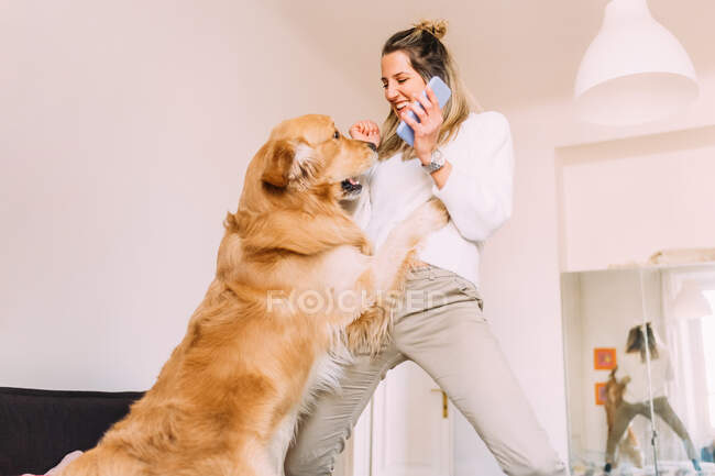 Italie, Jeune femme jouant avec un chien à la maison — Photo de stock