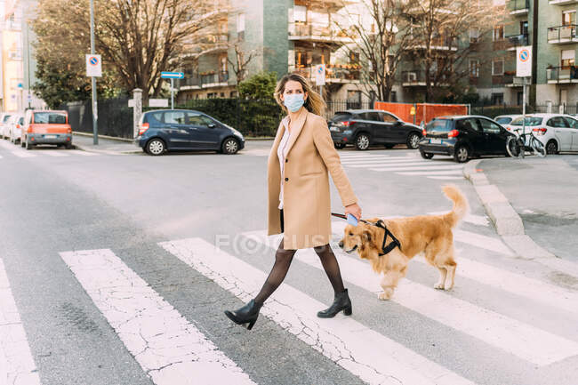 Italy, Woman with dog walking across street — Stock Photo