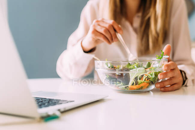 Італія: жінка їсть салат і дивиться на ноутбук. — стокове фото