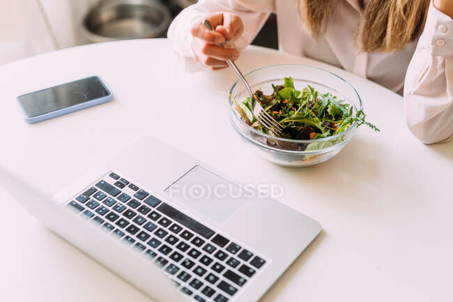 Italy, Woman eating salad and looking at laptop — Stock Photo