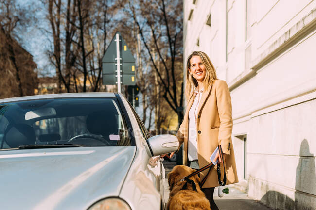 Италия, Женщина с собакой садится в машину — стоковое фото