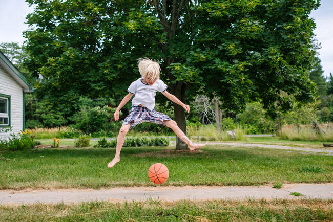 Canada, Ontario, Garçon sautant par-dessus le ballon de basketball en plein air — Photo de stock