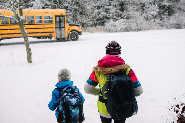 Канада, Онтаріо, вигляд дітей, що йдуть до шкільного автобуса снігом. — стокове фото