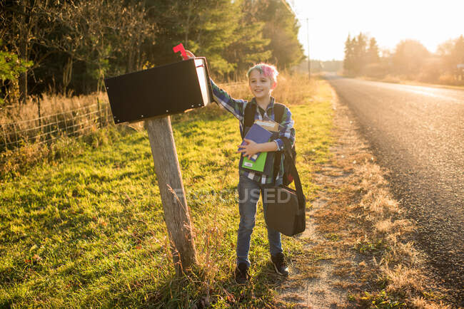 Canada, Ontario, Boy in piedi alla cassetta della posta sul ciglio della strada al tramonto — Foto stock