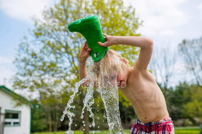 Canada, Kingston, Ragazzo senza camicia che versa acqua dallo stivale di gomma sulla testa — Foto stock