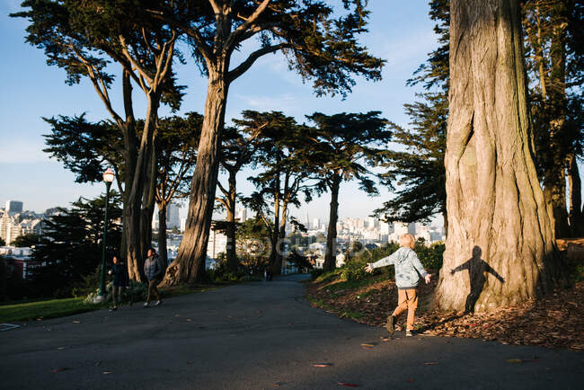 USA, California, San Francisco, Child with arms outstretched at tree trunk — Stock Photo