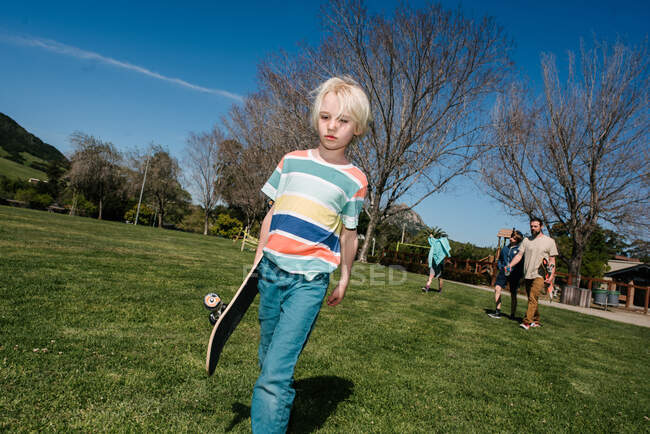 USA, California, Big Sur, Boy with skateboard walking in park — Stock Photo