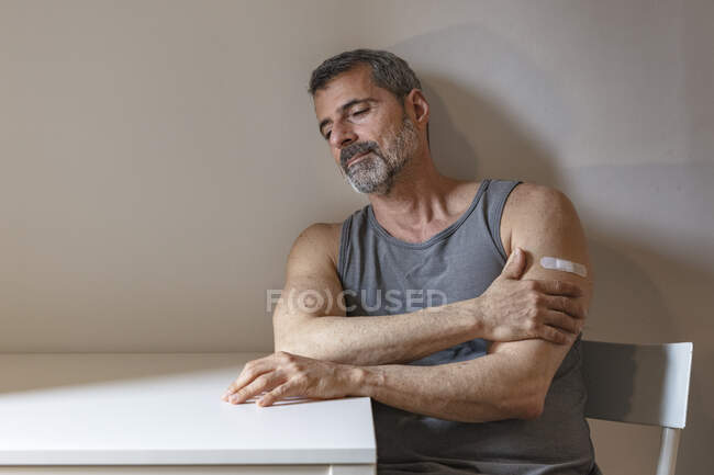 Франція, людина з бинтом на руці сидячи за столом. — стокове фото