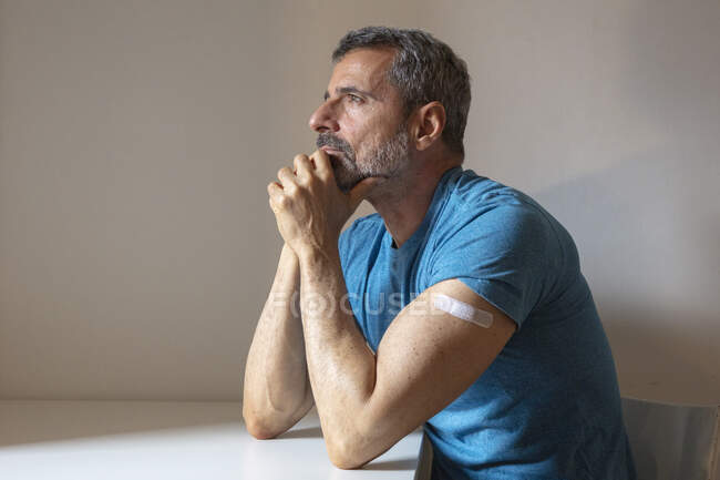 France, Homme avec bandage sur le bras assis à table — Photo de stock