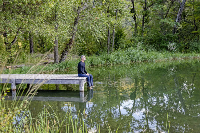 France, Alpes-de-Haute-Provence, Homme assis sur une jetée au bord du lac — Photo de stock