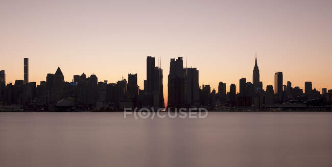 USA, NY, New York City, Midtown Manhattan seen across river at sunset — Stock Photo