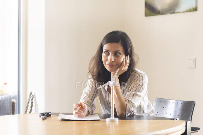 Німеччина, Фрайбург, Жіночий інженер сидить за столом з моделлю вітряної турбіни. — стокове фото