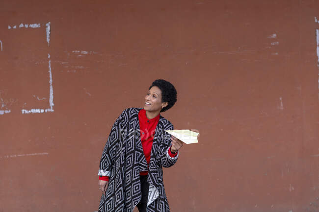 Italia, Toscana, Pistoia, Mujer sonriente sosteniendo avión de papel - foto de stock