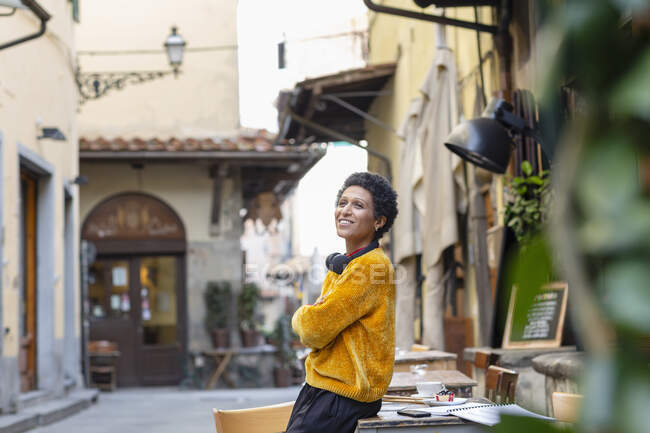 Italy, Tuscany, Pistoia, Smiling woman leaning against table in outdoor cafe — Stock Photo