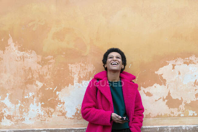 Italia, Toscana, Pistoia, Mujer de abrigo rosa riendo - foto de stock