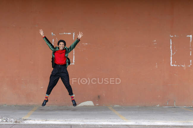 Italy, Tuscany, Pistoia, Smiling woman jumping against wall — Stock Photo