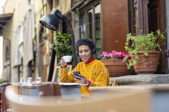 Італія, Тоскана, Пістоя, Жінка сидить у кафе на вулиці і користується смарт - телефоном. — стокове фото