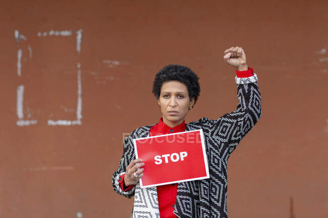 Italy, Tuscany, Pistoia, Woman holding stop sign and raising fist — Stock Photo