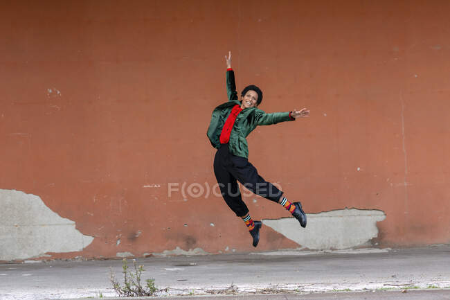 Italy, Tuscany, Pistoia, Smiling woman jumping against wall — Stock Photo