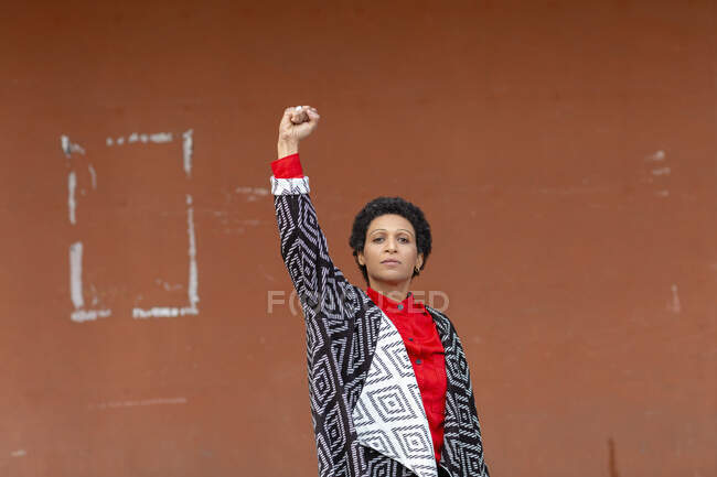 Italia, Toscana, Pistoia, Mujer de pie contra la pared y levantando el puño - foto de stock