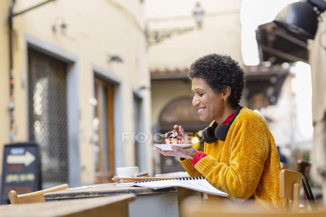 Italia, Toscana, Pistoia, Mujer sentada en la cafetería al aire libre y comiendo postre - foto de stock