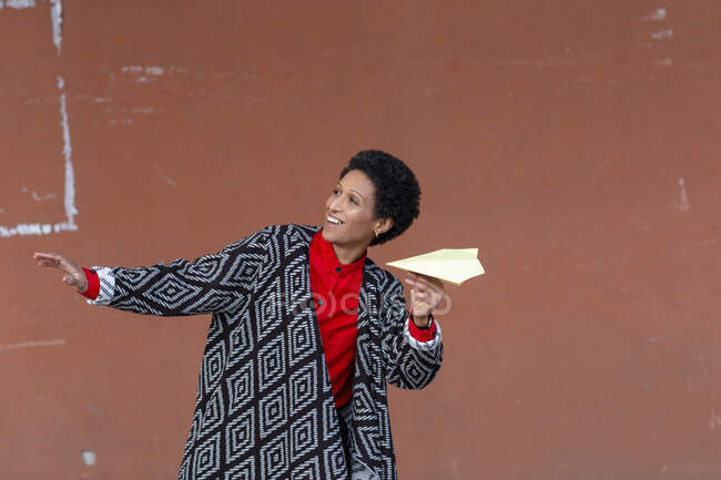 Італія, Тоскана, Пістоя, усміхнена жінка тримає паперовий літак. — стокове фото