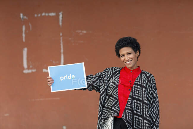 Italia, Toscana, Pistoia, Mujer sonriente sosteniendo el signo - foto de stock