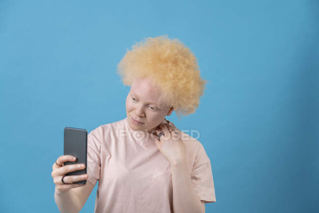 Studio foto di albino donna in possesso di smart phone — Foto stock