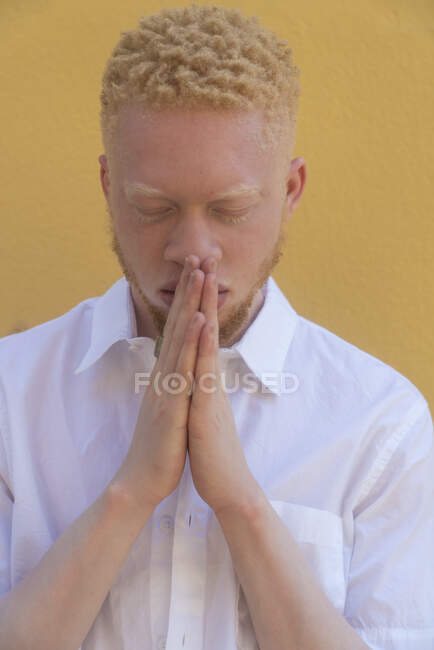Germany, Cologne, Albino man in white shirt against yellow wall — Stock Photo