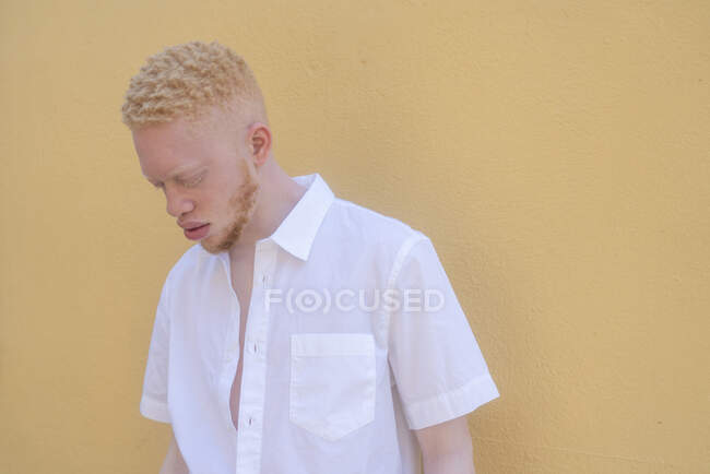 Alemanha, Colônia, Albino homem de camisa branca contra a parede amarela — Fotografia de Stock