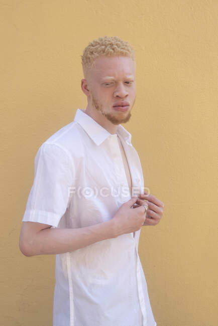 Німеччина, Кельн, Альбіно чоловік у білій сорочці проти жовтої стіни. — стокове фото