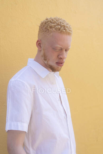 Alemanha, Colônia, Albino homem de camisa branca contra a parede amarela — Fotografia de Stock