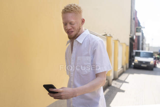 Німеччина, Кельн, Альбіно чоловік у білій сорочці, що тримає смартфон — стокове фото