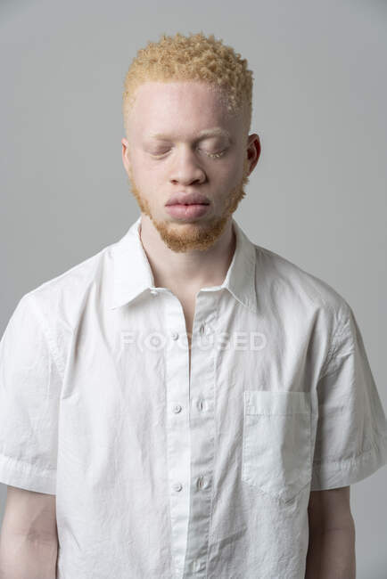 Studio portrait of albino man in white shirt with eyes closed — Stock Photo