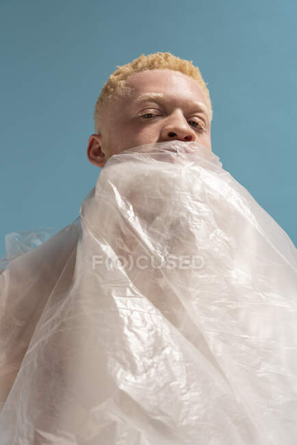 Studio portrait of albino man wrapped in plastic sheet — Stock Photo