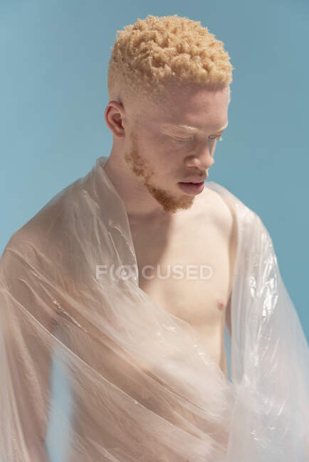 Студийный портрет альбиноса без рубашки, завернутого в пластиковую простынь — стоковое фото