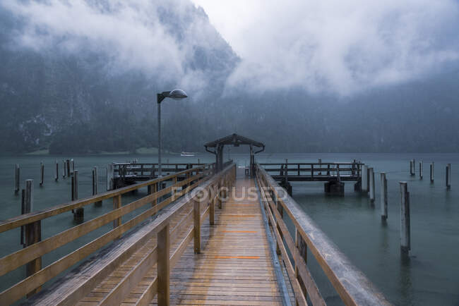 Alemanha, Baviera, Pier em Koenigsee e montanhas cobertas de nuvens — Fotografia de Stock