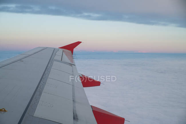 Ala de avião acima das nuvens ao pôr do sol — Fotografia de Stock