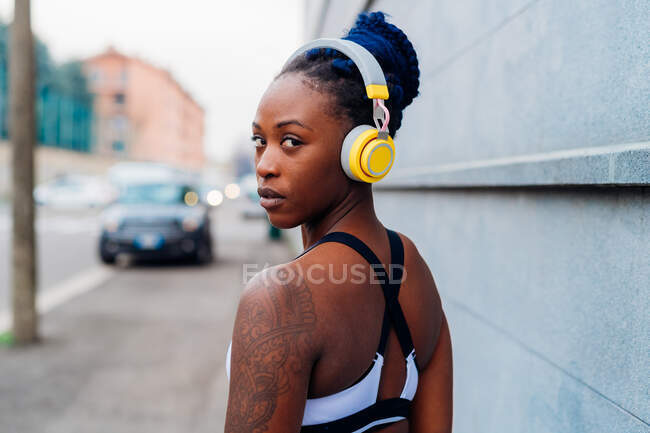 Italy, Milan, Portrait of woman in sports clothing and headphones in city — Stock Photo