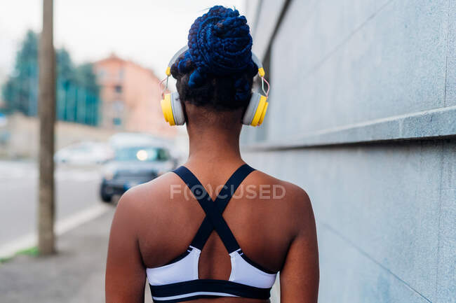 Itália, Milão, Vista traseira da mulher em roupas esportivas e fones de ouvido na cidade — Fotografia de Stock