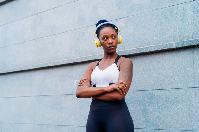 Italy, Milan, Portrait of woman in sports bra and headphones in city — Stock Photo